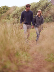 Naklejka na ściany i meble Happy couple, walking or holding hands in the countryside, nature or summer outdoor for hiking on valentines day date. Smile, man and woman at meadow for support, love or romantic connection together