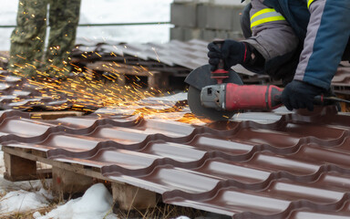 A worker cuts metal with a grinder at a construction site