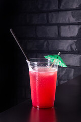 Red lemonade with ice cubes in a plastic glass