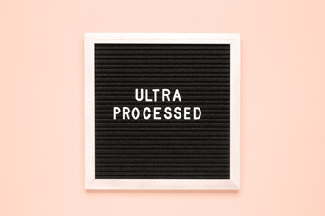 The word ultra processed on black letter board over isolated beige background