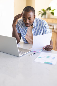 Young African American man reviews documents at home office