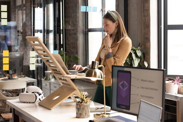 Young Caucasian woman works at a standing desk in a casual business office