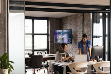 Asian woman and African American man collaborate in a modern casual business office