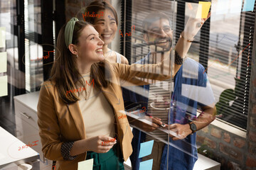 Young Caucasian woman and Asian colleagues engage in a casual business brainstorm in an office