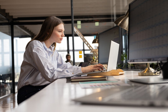 Young Caucasian woman works diligently at her casual business office desk