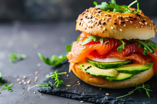 Freshly baked bagel topped with smoked salmon avocado and egg Served on a slate table
