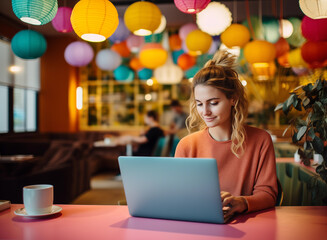 Entrepreneur woman working on laptop in a colorful and modern cafe shop, remote worker / digital nomad