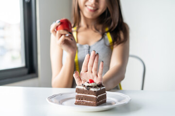 Choose right food for you health. Person eat dessert holding green apple and cake to compare...