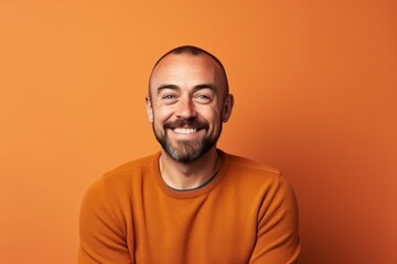 Obraz premium Portrait of a smiling man in orange sweater over orange background