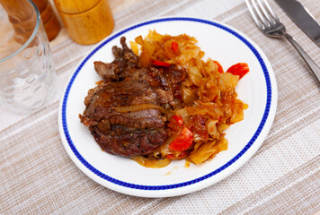 Appetizing pork cheeks with stewed cabbage served on platter