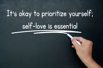 Hand writing It is okay to prioritize yourself affirmation on black board. Affirmation concept.