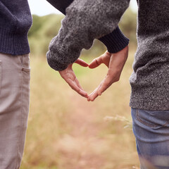 Heart hands, love and couple in the countryside together for hiking, romance or adventure closeup....