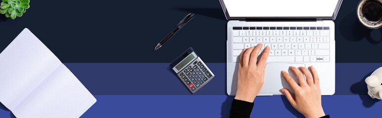 Woman using a laptop computer with a piggy bank and a calculator - 731553858