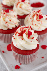 Red velvet cupcakes with cream cheese frosting and red sugar hearts. Delicious dessert for Valentines day. Selective focus, copy space.