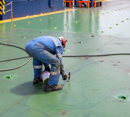 a ship crew is working or chipping during maintenance period on a cargo ship