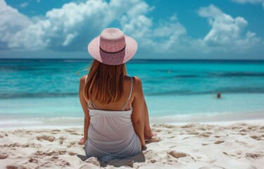 a woman is sitting on a beach sand and has a pink and white hat on