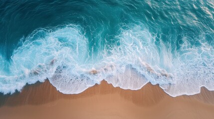 An aerial view of an empty beach, with the waves gently lapping at the shore
