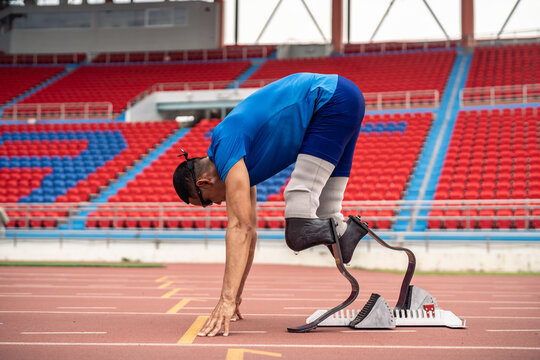 Asian athletes are disabled with prosthetic blades running at stadium. 