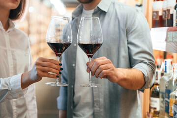 Glasses with drink. Take a sample. Man and woman are choosing wine in the shop