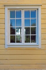 An old wooden white framed window on a yellow painted wall.