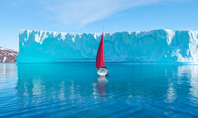 Giant iceberg breaks off near Greenland - Lone yacht with red sails - Greenland