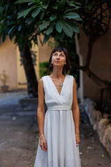 Tourist on vacation. Woman with an expression of freedom and pleasure. A girl in a white dress walks along the streets of the old city.