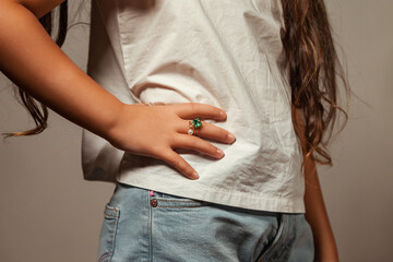 Close up of hand with ring on finger, child cover girl in white t-shirt showing jewelry, crop...