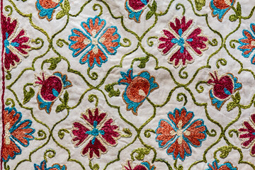 Bukhara suzani floral pattern. Uzbek silk satin base textile. Traditional gift or souvenir displayed at street market. Bukhara (Buxoro), Uzbekistan