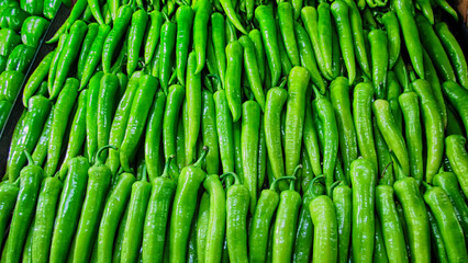 Fresh green green peppers lined up on the counter in the market