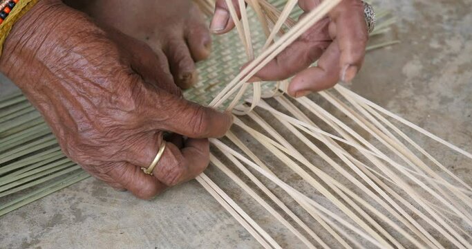 Old man's hands doing bamboo weaving, people making things from bamboo