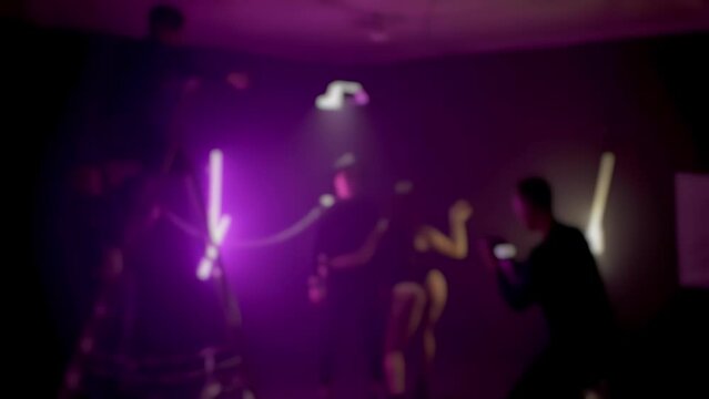 Backstage. On set amateur music video clip production. Blurred. Arthouse. Independent filmmakers. Cameraman films go-go girl doing private dance next to man in black suit tied up with chain