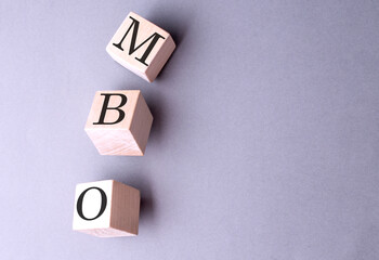 Word MBO on wooden block on the grey background