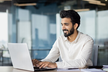 A man is sitting at a desk using a laptop computer