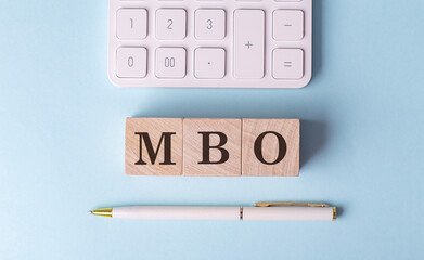 MBO on wooden cubes with pen and calculator, financial concept