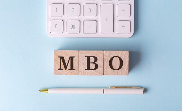 MBO on wooden cubes with pen and calculator, financial concept