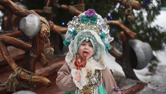 A little girl in a beautiful folk costume eats candy