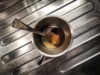 Coffee powder and a spoonful of honey in a metal cup on a metal background.