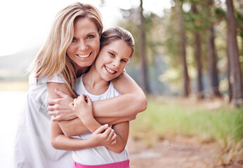 Fototapeta premium Mother, daughter and portrait in forest with happiness for bonding, support and hug on holiday in nature. Family, woman and girl child with face, smile and embrace on vacation, travel and adventure