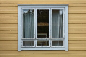 Fototapeta premium Old wood window with with white frame on a yellow painted wall.