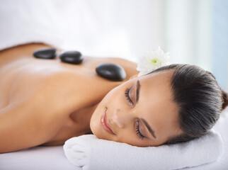 Obraz na płótnie Canvas Calm, hot stone and woman with massage at spa for wellness, health and back treatment. Self care, cosmetic and young female person sleeping for warm stone back therapy at natural beauty salon.