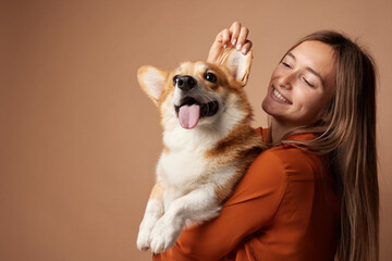 Obraz premium Girl hugging Pembroke Welsh Corgi on a beige clean background in the studio, love for animals