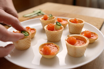 Canapes with pate, salmon and cucumber are being prepared.