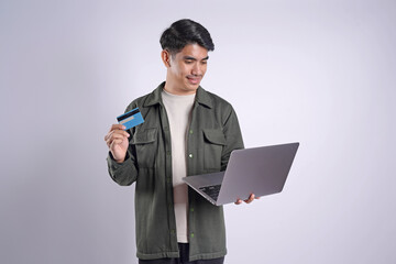 Online shop. Handsome man showing credit card and using laptop to order in internet isolated on white background