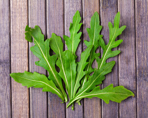 On wooden table there are several tender fresh leaves in way of palm tree. Leaves of edible greens form bouquet, fan of leaves, decorations of edible greens