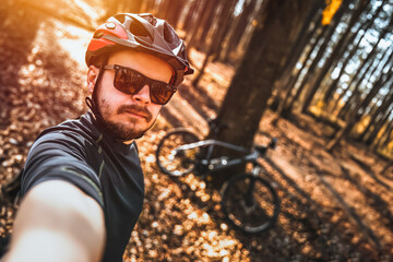 Sporty and Adventurous Man with Sunglasses and Helmet Snaps a Photo of Himself on a Bike
