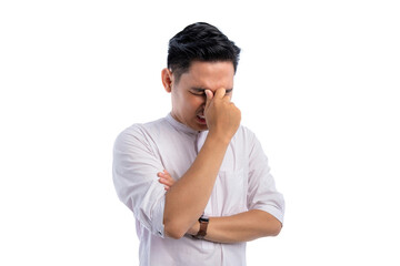 Unhealthy Asian Muslim man suffering from headache or migraine isolated on white background. Ramadan and Eid Fitr celebration concept