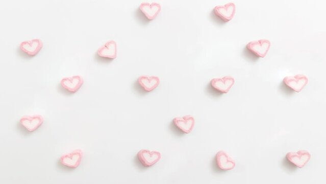 looping footage pattern marshmallow background. heart shape marshmallow, pastel pink and white color marshmallow pop up on white background. simple stop motion flat lay for Valentine background