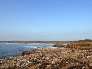 Rocky coast of the ocean bay, clear blue sky, ocean horizon, rocks