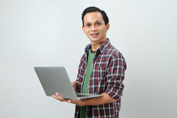 Happy asian indonesian man holding laptop computer on isolated background