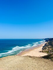 Rocky coast of the ocean bay, clear blue sky, ocean horizon, rocks